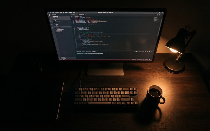 Developer workspace — code on screen, warm desk lamp